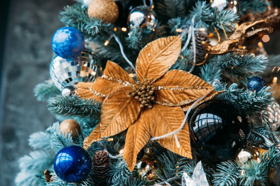 Árbol de Navidad decorado con flores artificiales y otros elementos navideños